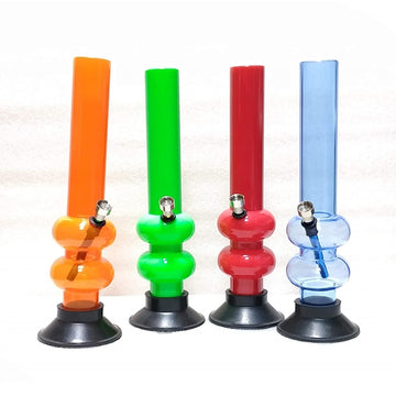 This image displays a collection of four Moksha 12-inch double bulb acrylic smoking water pipes, each featuring a vibrant, glossy finish. The water pipes come in an array of attractive colors: orange, green, red, and blue, each with a matching base that appears to be suction-mounted for stability.