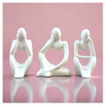 Three white ceramic figures in various poses on a pink background